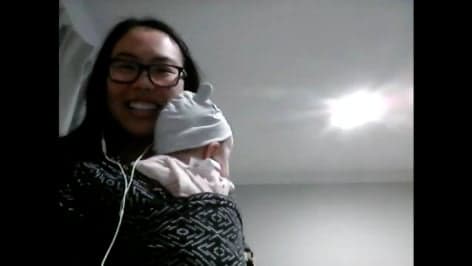Cindy smiling at the camera while holding a baby