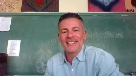 Eddie smiling at the camera in front of a chalkboard