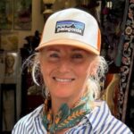 Andrea is wearing a Patagonia cap and a striped shirt while smiling at the camera.