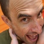 Jonathan smiling at the camera while holding a baby