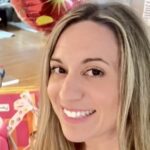 Sarah is a woman with long blonde hair who is facing the camera with a smile