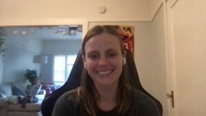 Abbie has long brunette hair and is sitting on a chair facing the camera with a smile as she talks about her insomnia experience