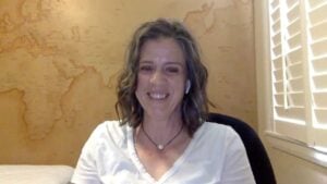 Amber has shoulder length hair and is wearing a white top. She is smiling as she talks about insomnia no longer being the boss of her life.