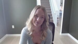 Woman sitting in a chair during a video call in a bright home office with a staircase in the background.