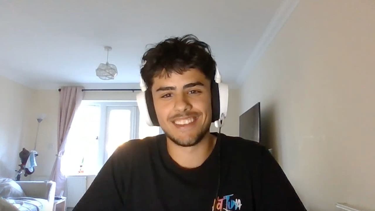 Smiling young man wearing a headset during a video call in a bright room.